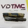 Metal cylindrical tool resting on a wrapped package on a white surface with a bold pink-outlined 'VDTM C' logo and '.COM' text; handwritten 'Since 1993' below.