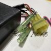 Close-up of electrical wiring with green and yellow inline connectors and a black plastic module surface visible in background.