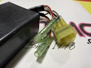 Close-up of electrical wiring with green and yellow inline connectors and a black plastic module surface visible in background.