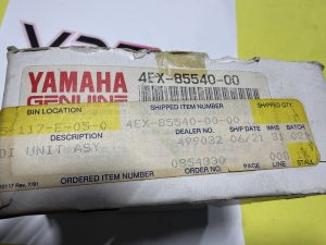 Worn Yamaha Genuine Parts box label with red YAMAHA text and a barcode showing part number 4EX-85540-00, along with shipping and item details on a yellow background