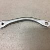 Curved silver metal lever with a small threaded hole at one end and a larger round hole at the other, lying on a gray surface