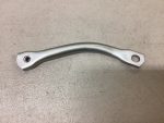 Curved silver metal lever with a small threaded hole at one end and a larger round hole at the other, lying on a gray surface