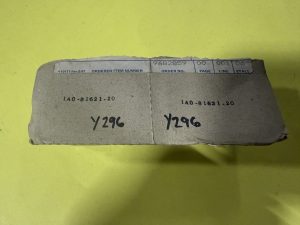 Worn cardboard package with a white perforated label showing 'ORDERED ITEM NUMBER' and 'ORDER NO.' on a bright yellow background.