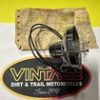 Logo patch reading ‘VINT’ with ‘DIRT & TRAIL MOTORCYCLES’ on a textured background against a bright yellow wall.