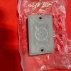 Grey plastic wall plate with a circular dial recess and two screw holes, resting on a clear plastic bag on a red surface