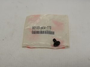 White plastic bag packaging with a barcode label reading 90103-HC4-770 and a small black Phillips-head screw resting on the bottom right.