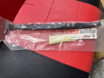 Long black Yamaha genuine-parts tool in clear plastic bag with label visible on a red-seat background.