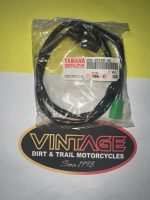 Bagged Yamaha genuine parts cable with a green connector, labeled 'YAMAHA Genuine Parts & Accessories,' on a Vintage Dirt & Trail Motorcycles backdrop.