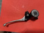 Close-up of a black bicycle brake lever with a silver lever arm on a red work surface; brake reservoir cap visible.
