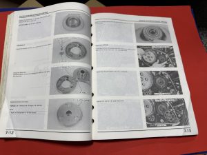 IMG_2155 Open two-page repair manual showing clutch system photos and numbered gear diagrams with labeled parts and assembly steps.