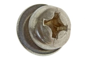 Close-up of a rusty metal bolt head with a cracked, square-shaped recess surrounded by a circular flange (damaged fastener).