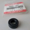 Black rubber oil seal with a hollow center placed on a light surface next to a Suzuki Motor Corporation parts bag with a barcode and red label