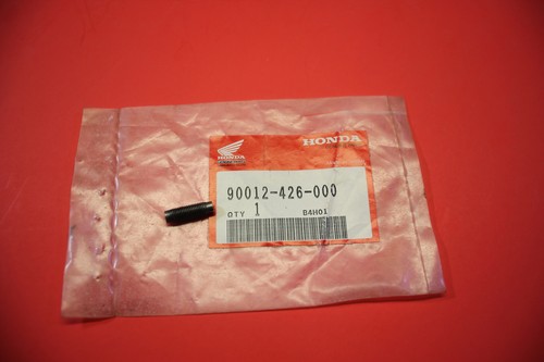Pink plastic bag with a Honda part label reading 90012-426-000; a small black pin rests on the bag on a red surface.