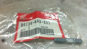Small Honda genuine-part bag labeled 90136-KA3-831 with a metal bolt beside it on a light surface.
