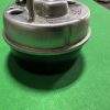 Close-up of a metal mechanical component with a threaded bolt on top, set on a bright green surface.
