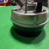 Close-up of a metal mechanical base with a threaded bolt and black adjustment knob on a green surface.
