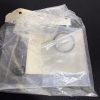 Close-up of a clear plastic bag containing white plaster or ceramic pieces with holes, resting on a dark surface.