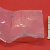 Clear plastic bag on a red surface containing two small silver U‑shaped metal fasteners, with a receipt-like label to the right.