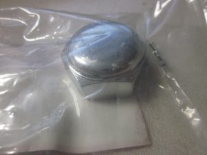 Close-up of a shiny metal cap inside clear plastic wrap on a gray surface.