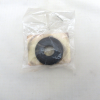 Small plastic bag containing a black circular gasket with a central hole on a beige backing surface