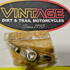 s-l1600 Logo reading 'VINTAGE DIRT & TRAIL MOTORCYCLES since 1993' on a black oval sign; below it, a sealed plastic bag with a metal motorcycle part rests on a white surface.