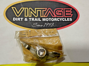 s-l1600 Logo reading 'VINTAGE DIRT & TRAIL MOTORCYCLES since 1993' on a black oval sign; below it, a sealed plastic bag with a metal motorcycle part rests on a white surface.