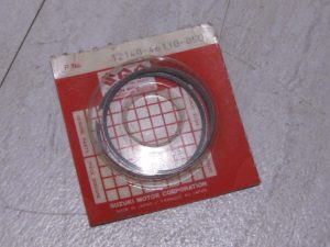 Red Suzuki motor parts packaging with a circular metal seal ring inside, Made in Japan label visible.