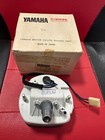 Yamaha parts kit with a small metal motorcycle component on a red surface, box in the background.