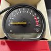 Car instrument gauge with a yellow needle pointing near zero, in a cardboard box.