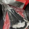 Black circular component sealed in a clear plastic bag on a red surface.