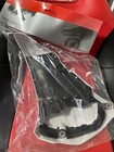 Black circular component sealed in a clear plastic bag on a red surface.