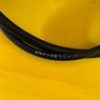 Curved black cable resting on a bright yellow surface, close-up view