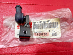 s-l500 Small black plastic automotive component with a side nozzle and mounting hole on a pink textured surface, resting on a bag with a barcode label.